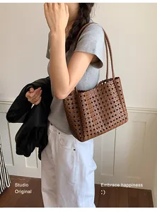 Detailed view of a stylish woman carrying a brown woven hollow-out tote bag for commute.