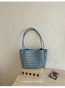 Detail view of a light blue hollow-out tote bag styled with modern architectural props