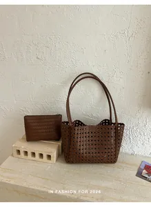 Close-up of brown woven hollow-out tote bag and matching clutch set on marble surface