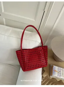 Detailed macro view of a stylish red hollow-out woven tote bag on a white sofa scene