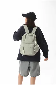 Rear view of a lightweight sage green nylon backpack worn by a model for daily commute