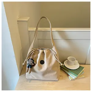 Beige lightweight nylon bucket bag with drawstring closure and cute teddy bear charm