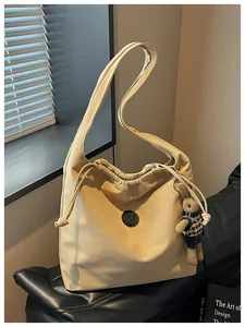 Detailed view of a beige nylon hobo bag with a cute rabbit keychain accessory