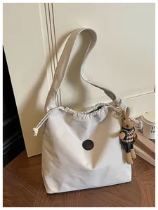 Detail of off-white nylon drawstring shoulder bag with a cute rabbit charm accessory.
