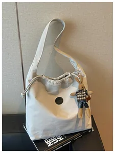Detail view of lightweight grey nylon shoulder bag with a cute rabbit charm accessory
