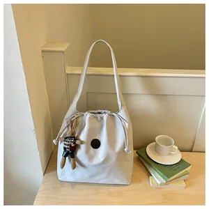 Detailed view of a lightweight grey nylon bucket bag with a cute rabbit keychain