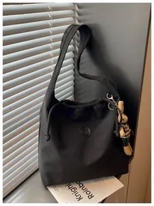 Detail view of a lightweight black nylon shoulder bag with a drawstring and rabbit charm.