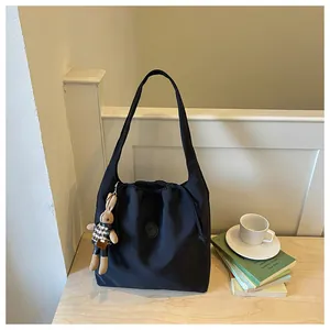 Detail of black nylon shoulder tote bag with drawstring closure and rabbit charm