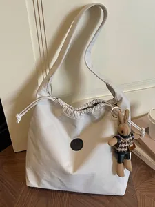 Minimalist off-white nylon shoulder bag with drawstring and cute bunny charm accessory