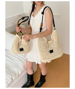 Hand-woven cream straw tote bag in two sizes shown on model for beach vacation style