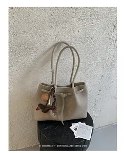 Detail view of a beige minimalist tote bag featuring a cute dachshund bag charm.