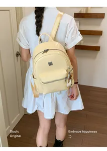 Women's stylish cream textured backpack worn as a fashionable daily commuter bag.