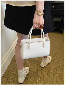 Chic white commuter handbag held by a model, showcasing its elegant and compact design