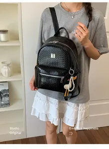 Woman wearing a black woven texture backpack with a cute duck pearl keychain accessory