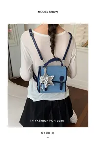 Vista trasera de una elegante mochila de mezclilla azul para mujer con un dije de estrella