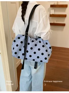 Close-up view of a blue polka dot large capacity tote bag worn by a model in casual style