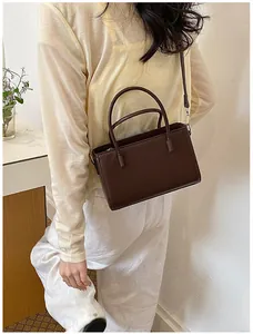 Detailed view of a dark brown structured handbag worn by a model for a chic look