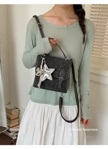 Elegante bolso bandolera gris oscuro texturizado con un colgante decorativo de estrella