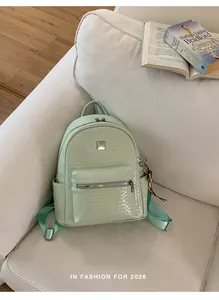 Stylish mint green woven texture backpack for women displayed on a cozy white sofa.