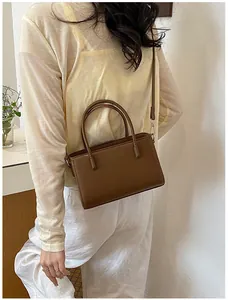 Detail of a stylish brown leather handbag worn by a model in a minimal setting.