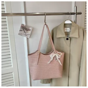 Détail d'un sac cabas tissé rose avec nœud en dentelle sur un porte-vêtements