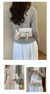Detailed view of a white polka dot crossbody bag featuring a cute rabbit charm on a model.