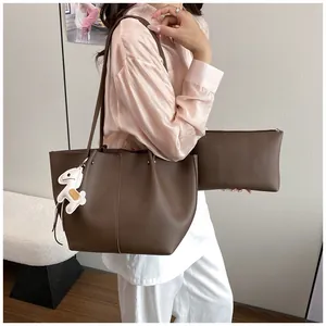 Close-up detail of a brown pebbled leather tote bag with a matching pouch and horse charm