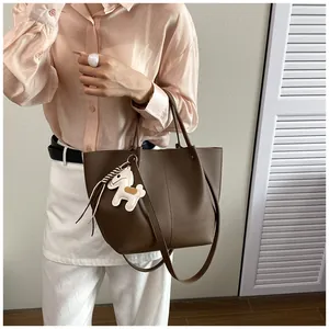 Detailed view of a premium brown leather tote bag with a horse charm carried by a model.