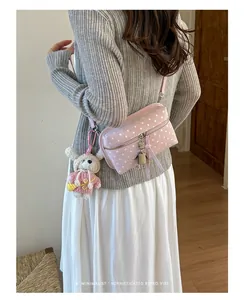 Detailed close-up of a pink polka dot crossbody bag featuring cute bunny and robot charms.