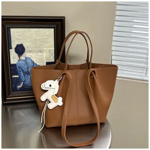 Elegant brown leather tote bag with horse charm in a minimalist office setting