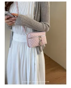 Elegant pink polka dot crossbody phone bag worn by a model in a minimal chic style outfit