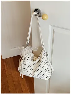 Große weiße Polka-Dot-Tasche mit Band und Perlenanhänger, hängend an einem Türgriff