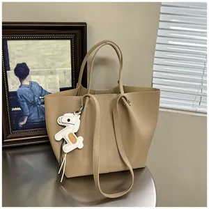 Detailed view of a high-quality beige leather tote bag featuring a cute horse charm