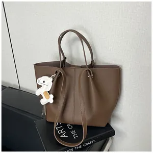 Detail view of a brown pebbled leather tote bag with a white animal charm decoration