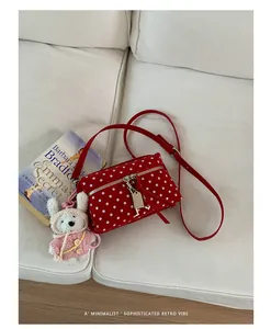 Detailed view of a red polka dot crossbody bag with a cute plush rabbit charm
