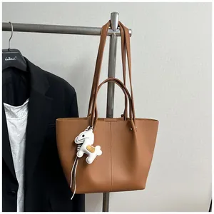 Elegant brown pebbled leather tote bag with white horse charm detail on a rack