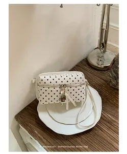 Detailed view of a retro white shoulder bag with black polka dots on ceramic plates