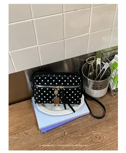 Detail view of black polka dot crossbody bag with robot charm on kitchen counter
