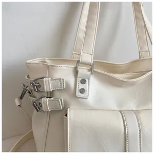 Close-up of a stylish cream white tote bag detailing silver buckles and premium leather
