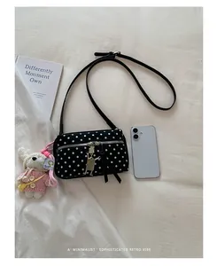 Detail view of a black polka dot crossbody bag with a cute white bunny plush charm