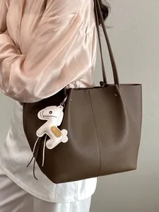 Minimalist brown pebbled leather tote bag with stylish white horse charm accessory