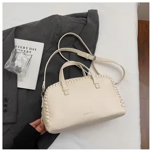 Detailed view of a cream pebbled leather Boston bag with unique woven edge design.