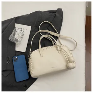 Macro view of cream Boston handbag with woven edges and decorative ball charms