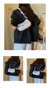 Detailed view of a stylish white bow polka dot underarm shoulder bag worn by a model