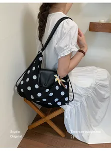Modella con zaino multifunzionale a pois bianchi e neri in un ambiente studio luminoso.
