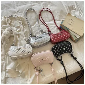 Selection of colorful polka dot bags with bow-knot details and charms on white fabric