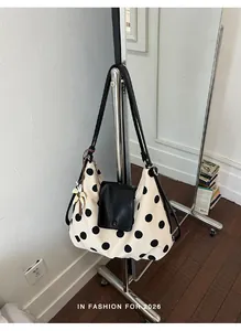 Borsa tote grande in tela a pois appesa a uno stand appendiabiti dal design minimalista