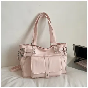 Pink faux leather tote bag with buckle details shown in a lifestyle office setting