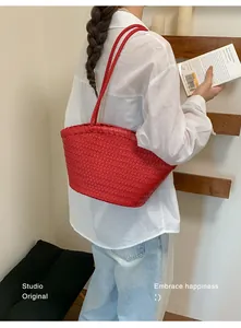 Vista macro detallada de un bolso de hombro tejido rojo sostenido por una mujer.
