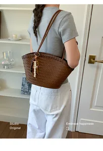 Vista detallada de un bolso tote trenzado marrón con colgante de cuentas de madera en modelo